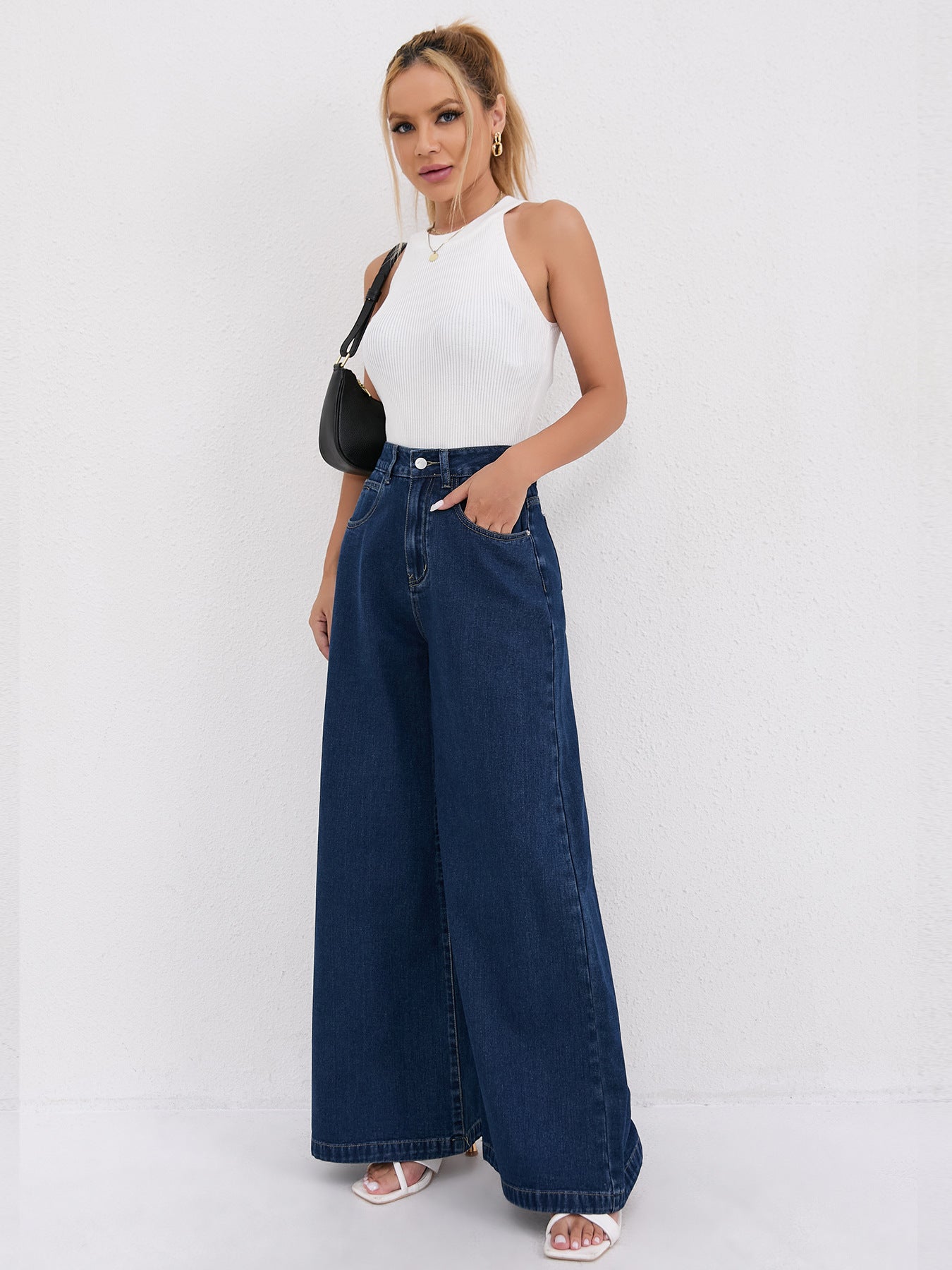 Wide leg dark blue denim jeans paired with a white sleeveless top for modern fashion