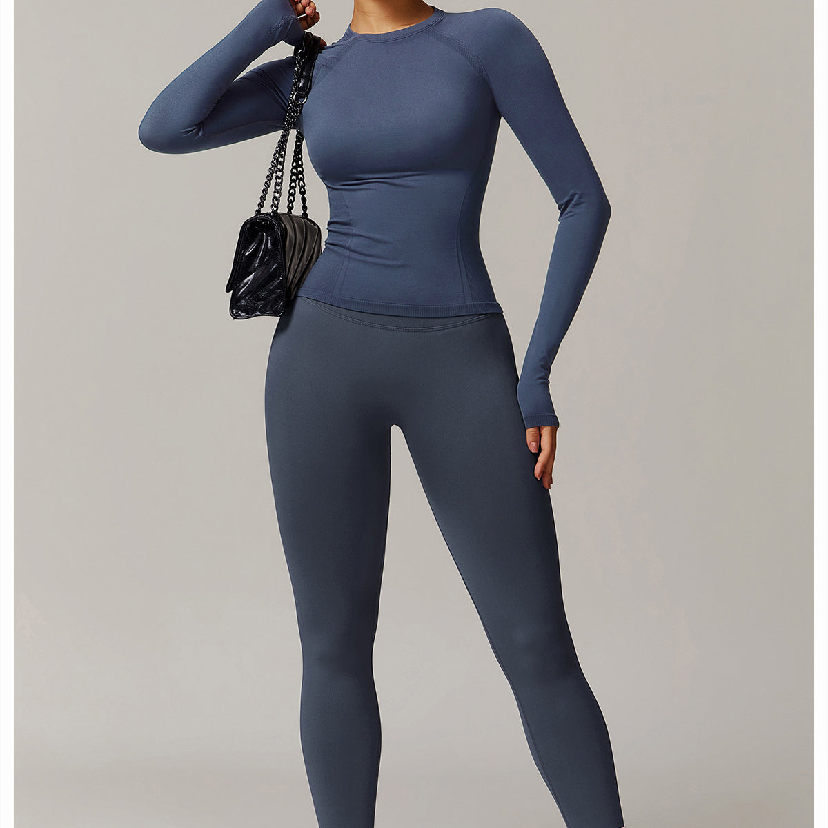 Woman in blue long sleeve athletic wear styled with a black purse, showcasing fashionable langry