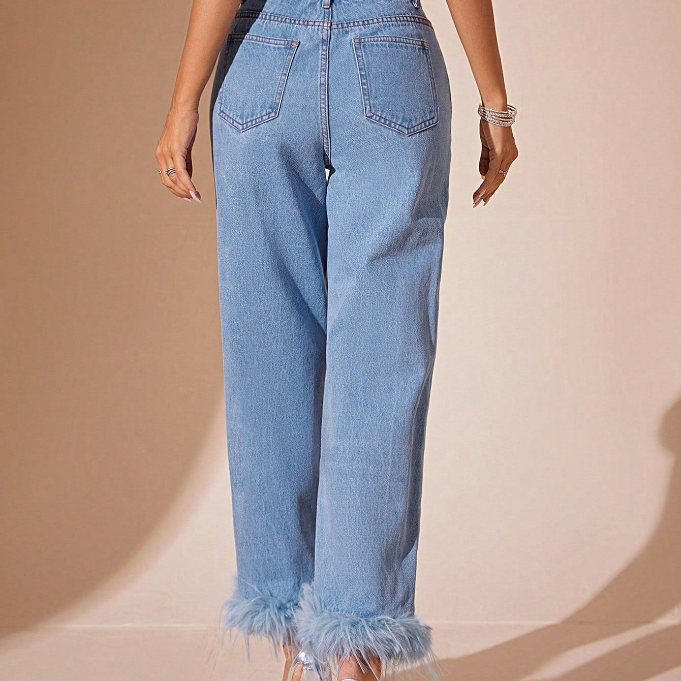 Light blue denim jeans with furry stitching and feather trim on cuffs, straight fit