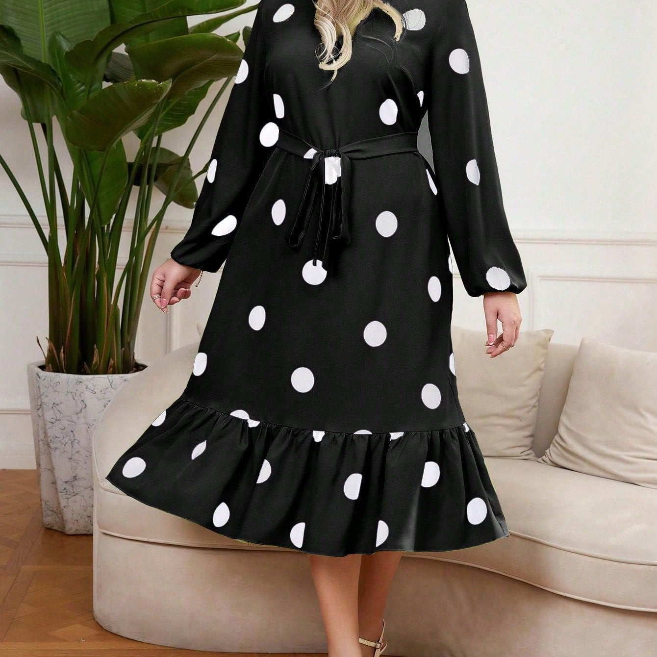 Woman wearing a black midi dress with white polka dots and a lotus leaf hem