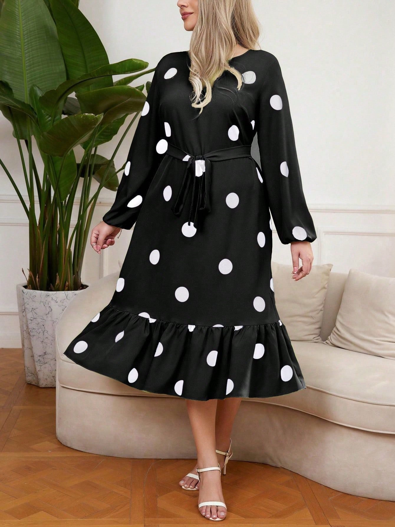 Woman wearing a black midi dress with white polka dots and a lotus leaf hem