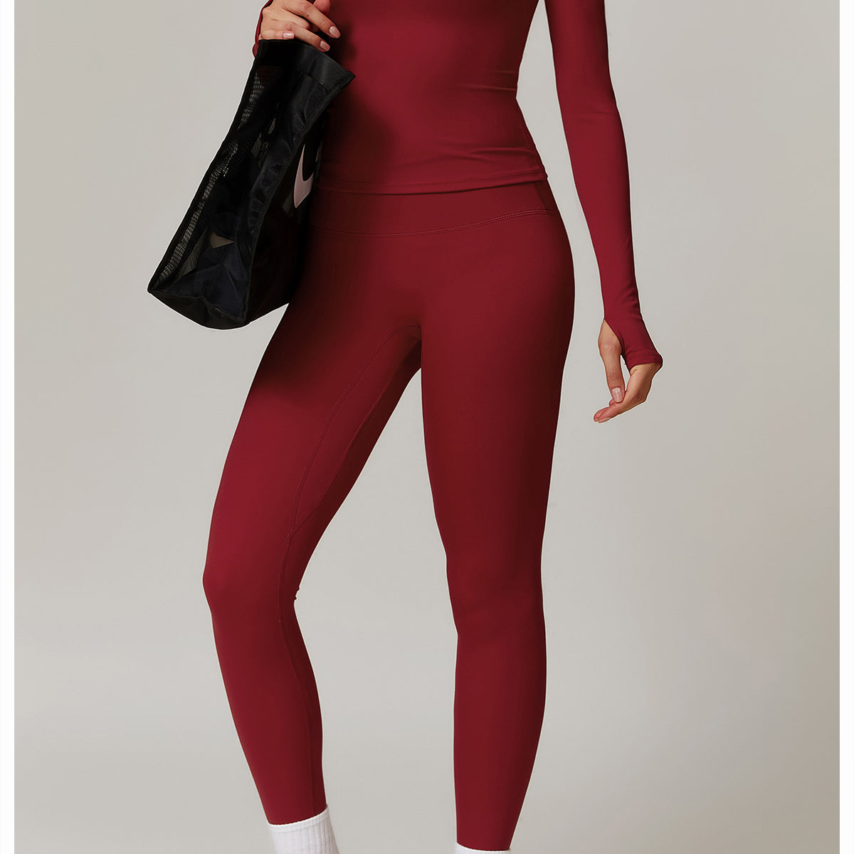 Burgundy langry turtleneck jumpsuit with sneakers and a black handbag for fitness fashion