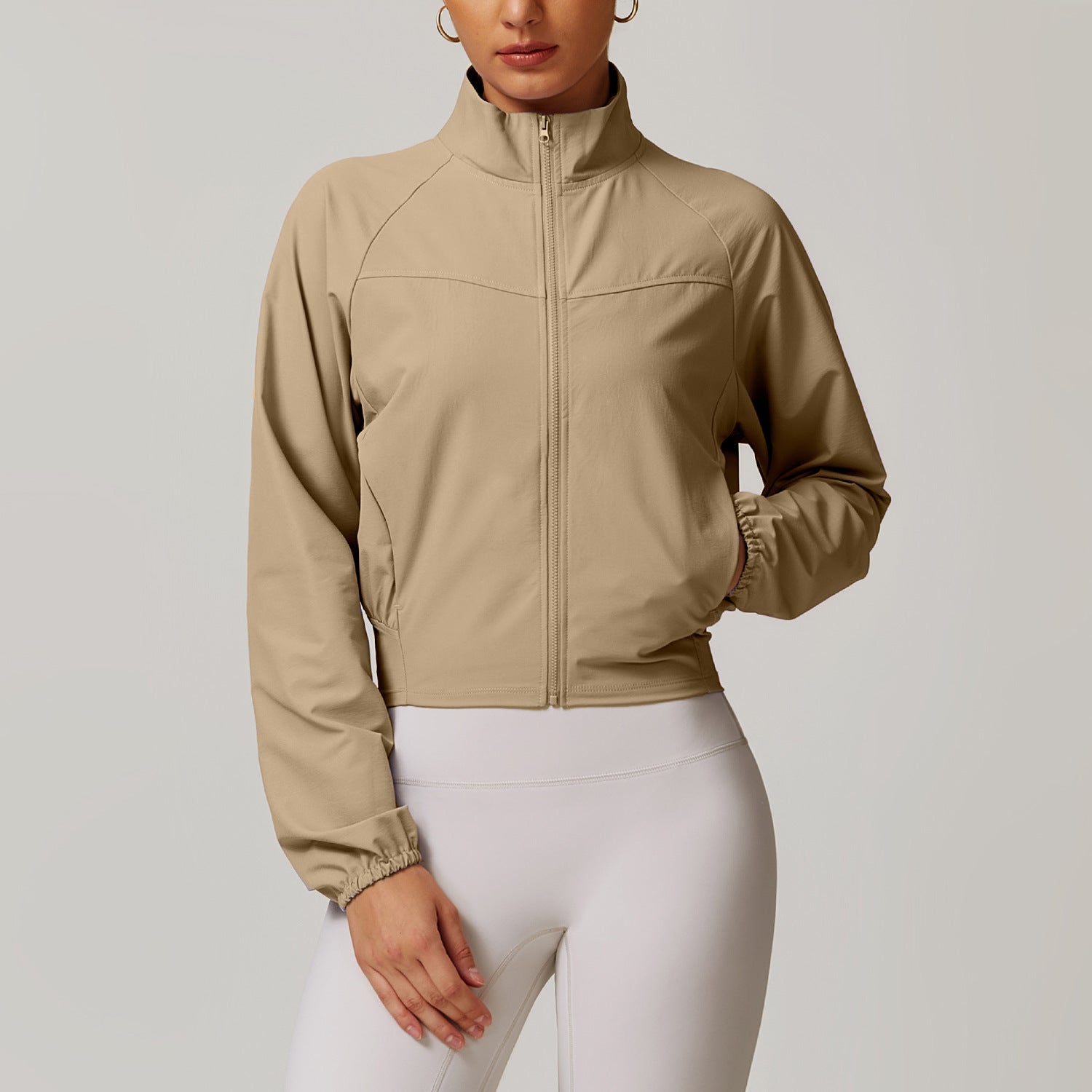 Beige cropped zip-up athletic jacket featuring a mock neck collar for active fashion