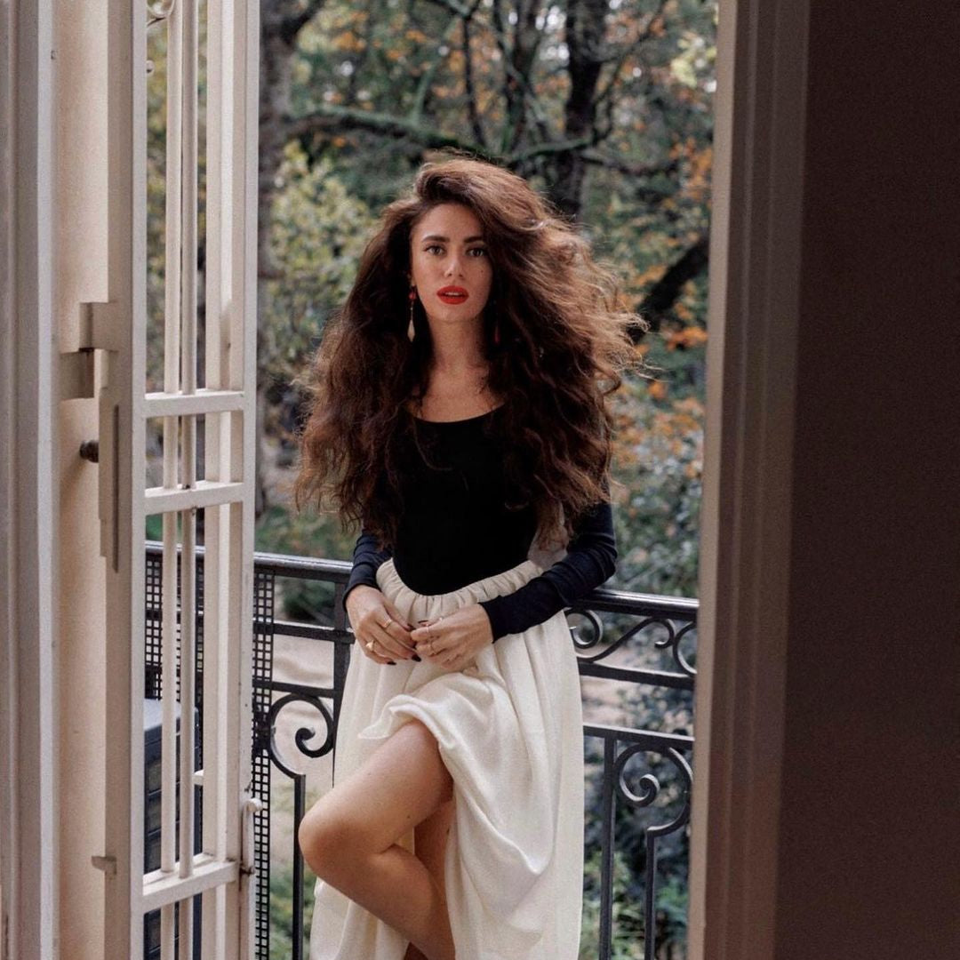 Woman in Elegant Hepburn Dress posing at a French balcony, showcasing langry fashion ملابس
