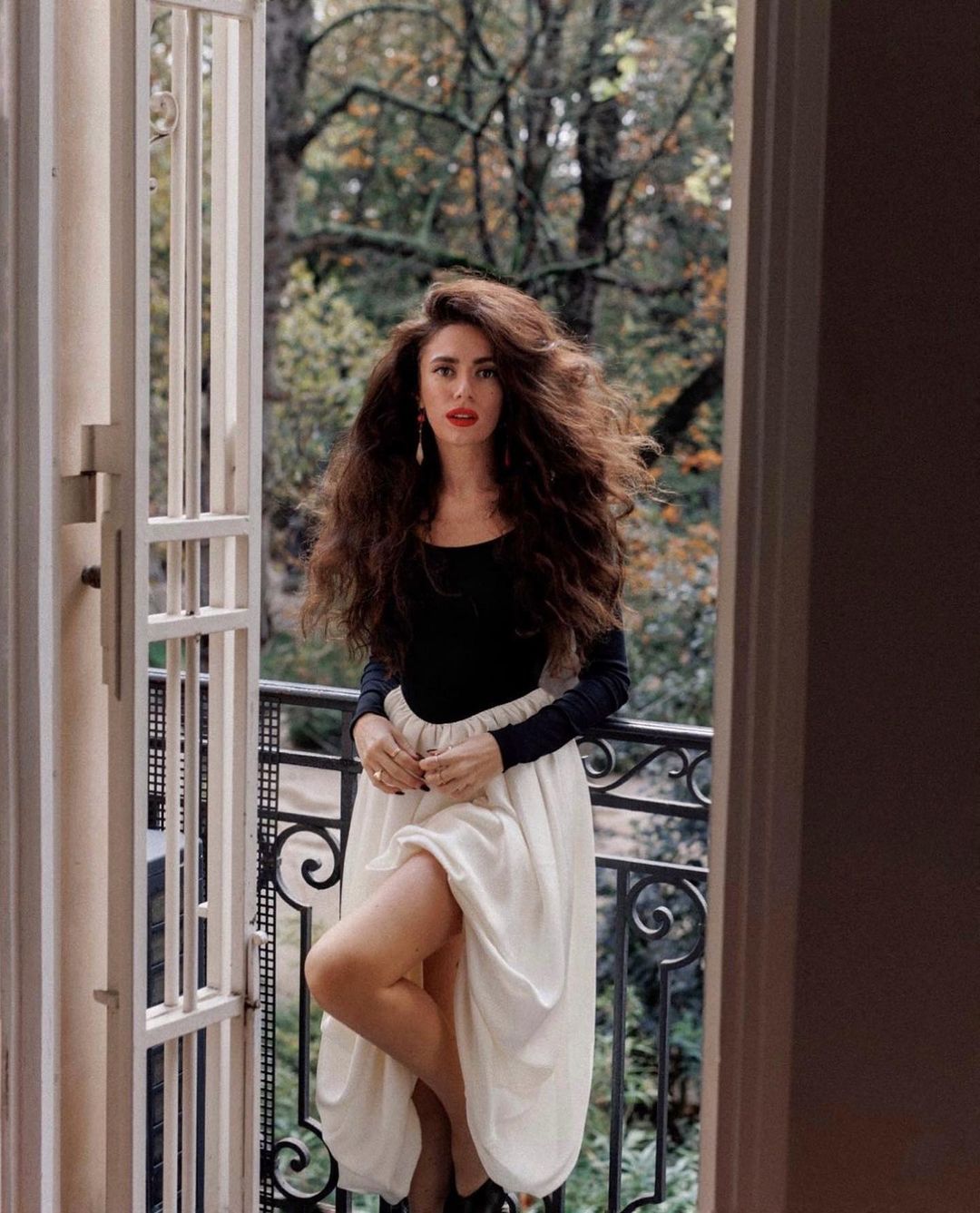 Woman in Elegant Hepburn Dress posing at a French balcony, showcasing langry fashion ملابس