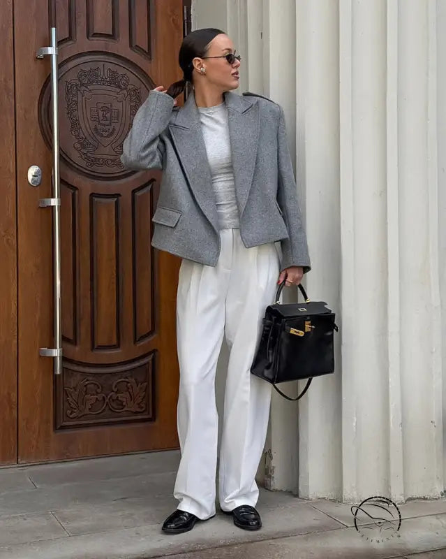Grey wool large collared short blazer with black buttons, white trousers, sunglasses, handbag