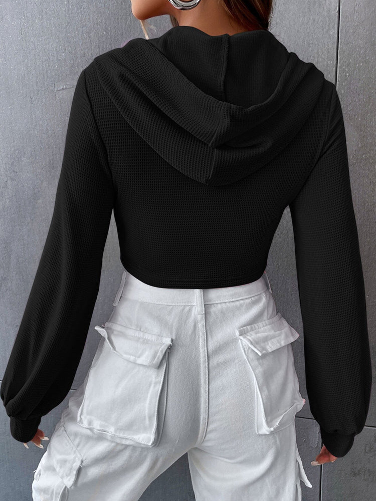 Black textured long-sleeved cropped hoodie with white cargo pants, stylish short faux fashion