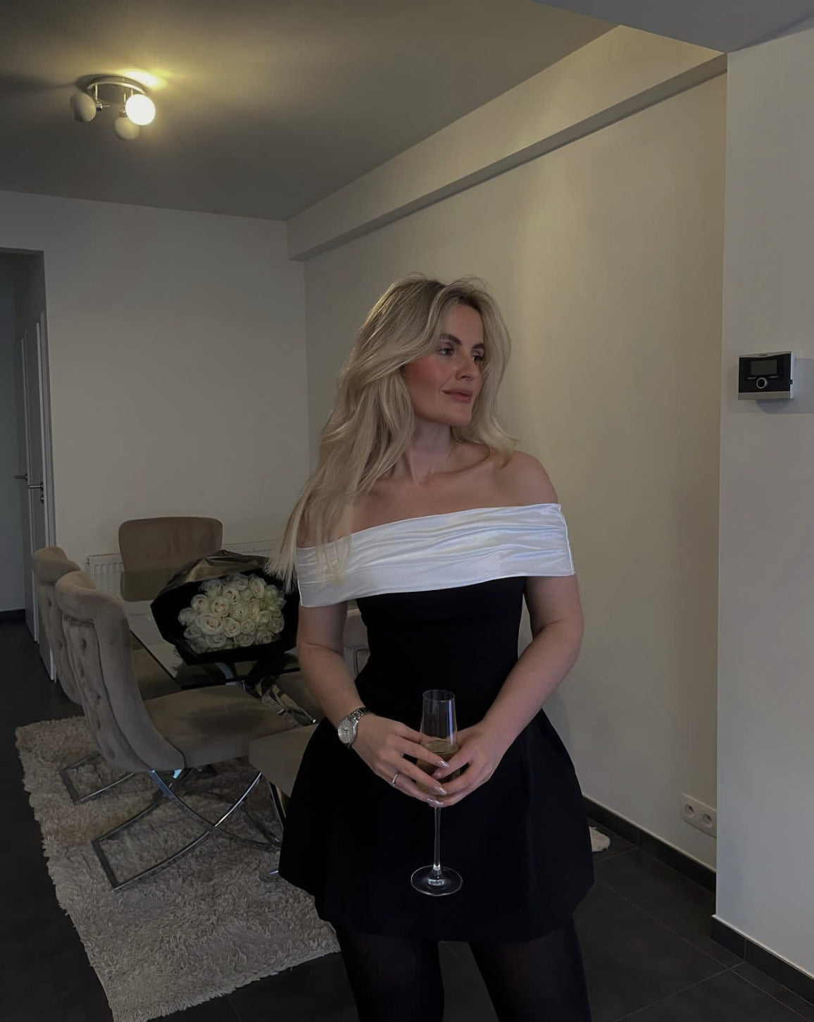 Elegant woman in Black White Swing Design Bow Dress holding champagne showcasing fashion style