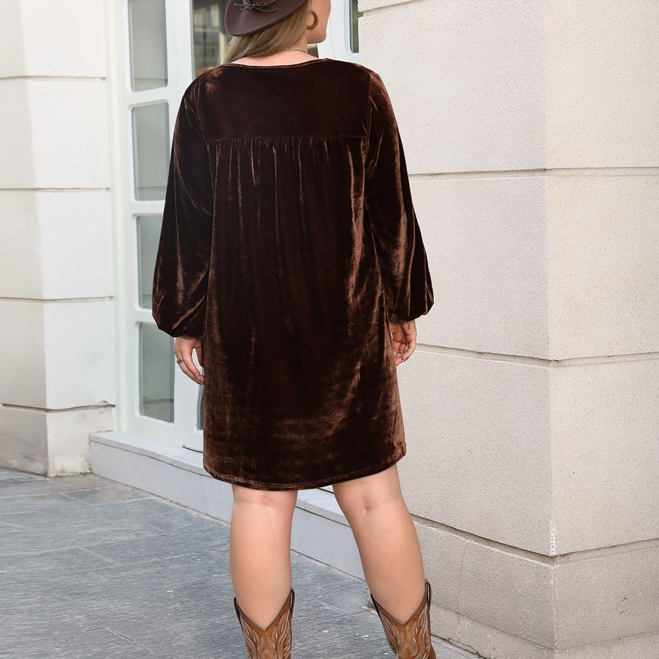 Woman in a brown velvet mini dress with cowboy boots wearing a loose slimming casual dress