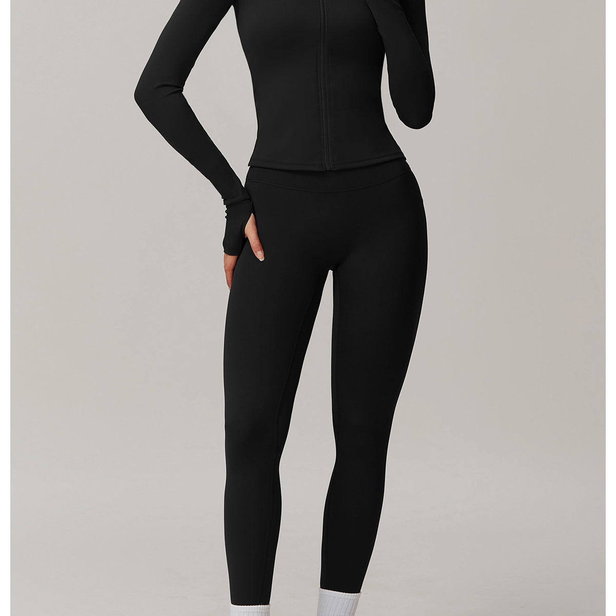 Black long-sleeved athletic jumpsuit styled with white socks and gray sneakers for langry fashion