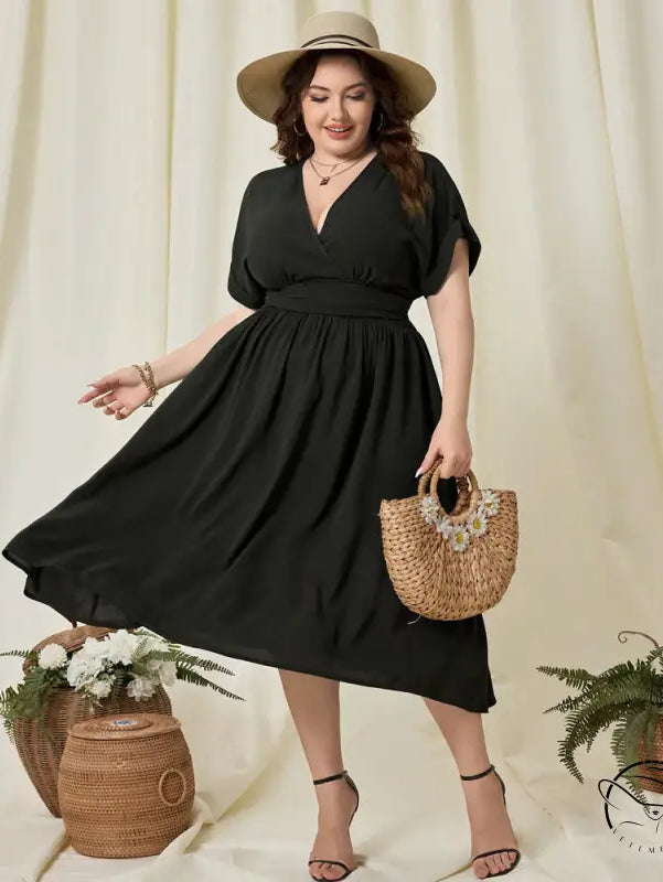 Plus-size woman in vacation high waist A-line black midi dress with V-neck, short sleeves, straw hat, bracelets, straw bag, and black high-heeled sandals