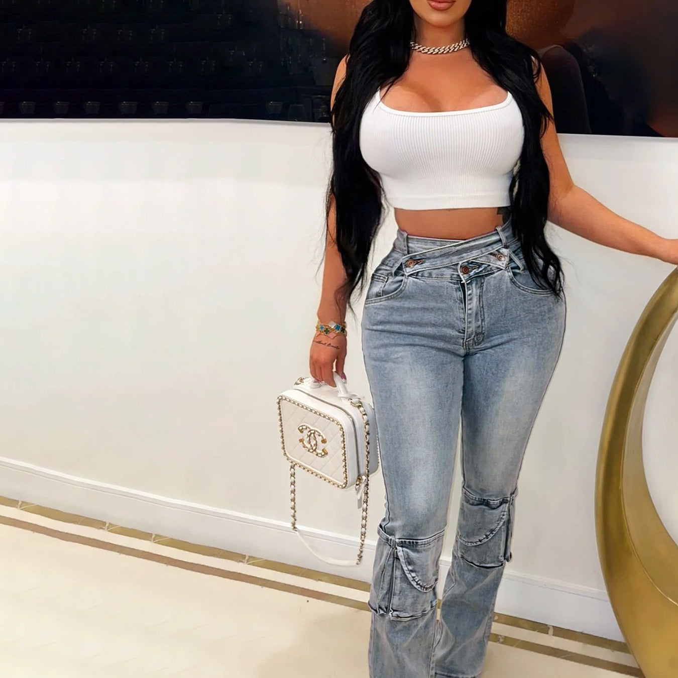 Woman in white crop top and light-wash chain-detailed denim trousers showcasing langry fashion