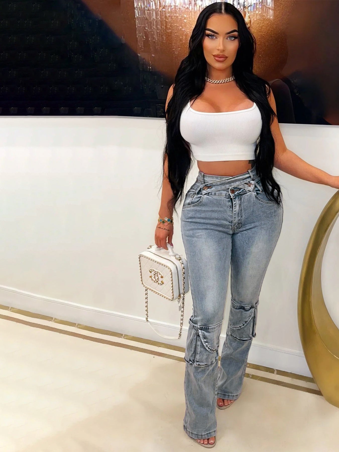 Woman in white crop top and light-wash chain-detailed denim trousers showcasing langry fashion