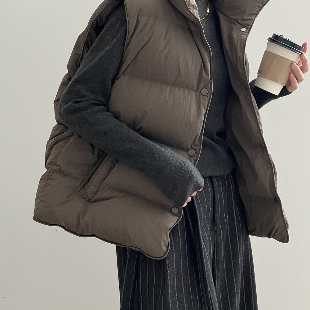 Brown puffy down vest over a dark pinstriped dress in stylish fashion ملابس