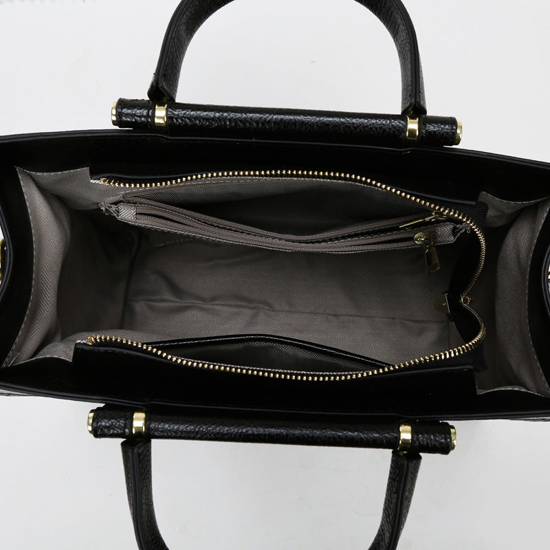 Black leather handbag with dual handles and zippered compartments for elegant fashion