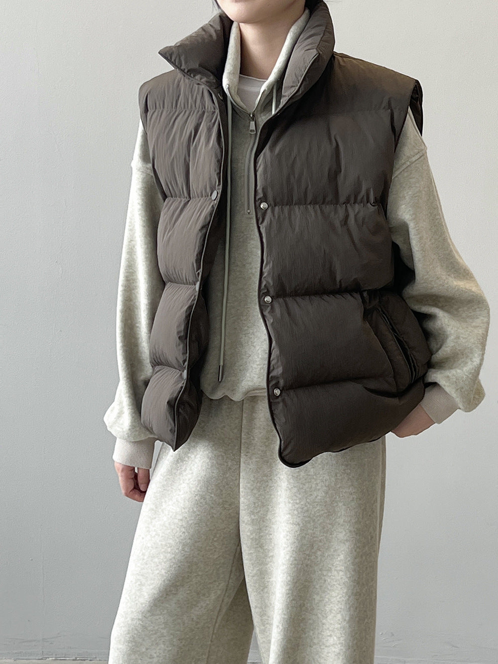 Dark gray puffy down vest over cream sweater and pants, stylish langry fashion ملابس