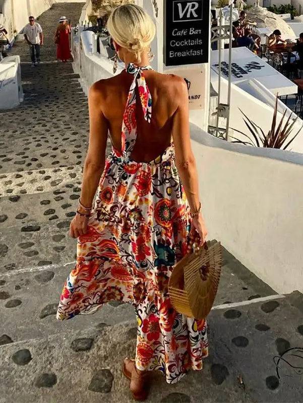 Woman in summer halter backless holiday dress with floral white maxi, bamboo bag