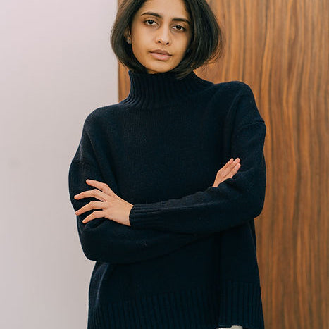 Langry fashion black turtleneck sweater with white pants on wooden door