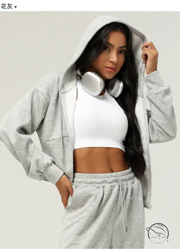 Woman in gray hooded tracksuit wearing headphones, casual cardigan sweater