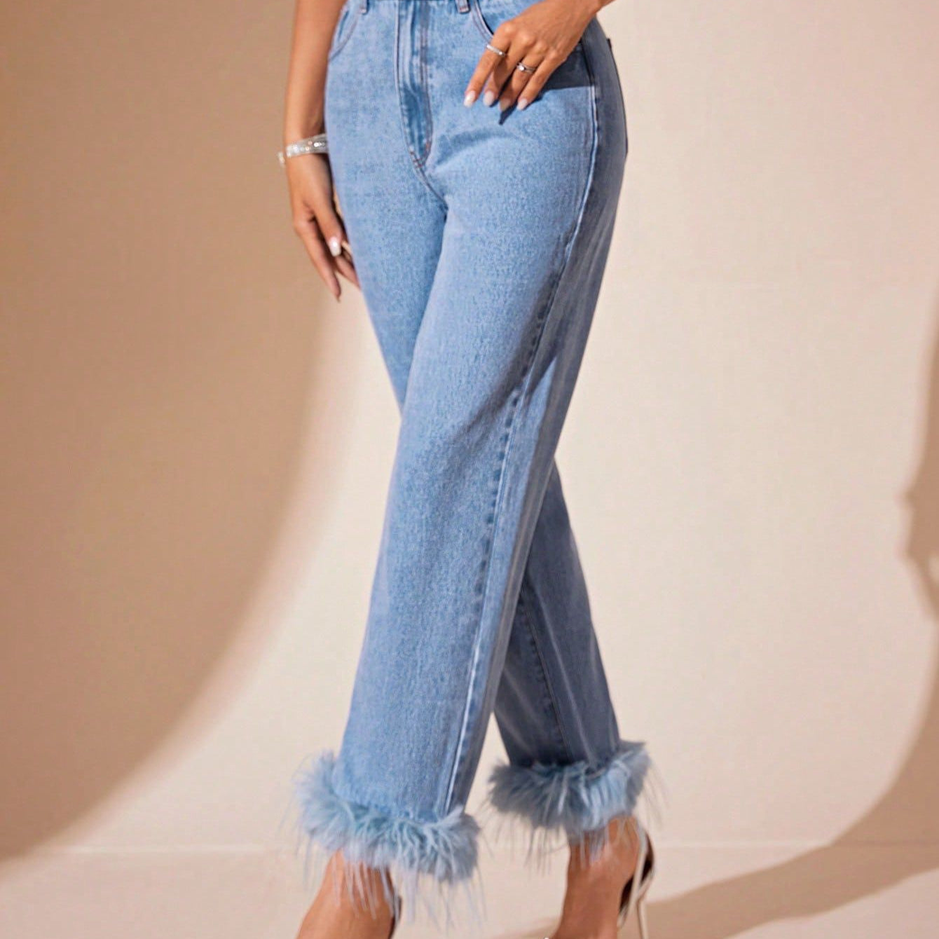 Light wash blue denim jeans with feathered cuffs featuring furry stitching and a straight fit
