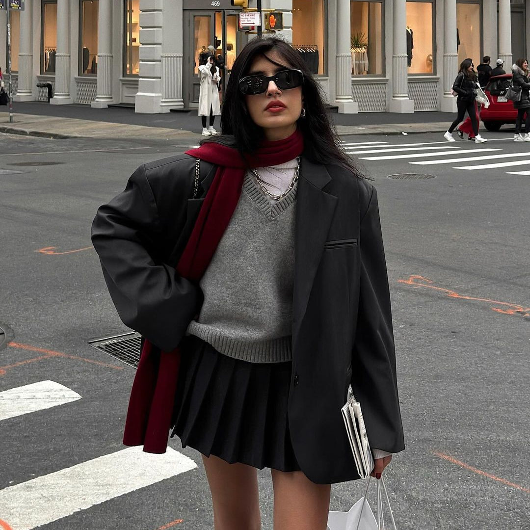 Fashionable winter outfit with dark blazer, pleated skirt, gray sweater, and burgundy scarf