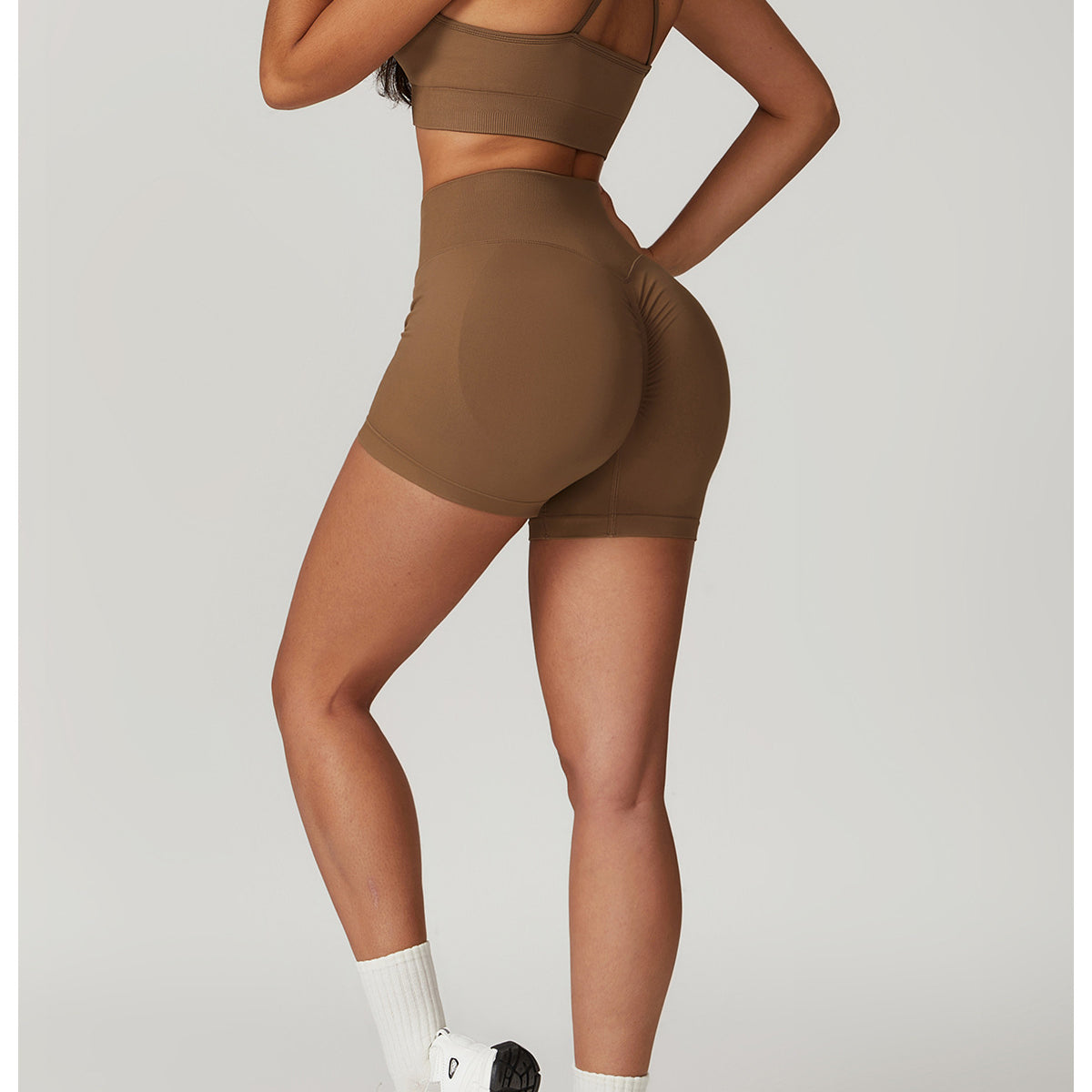 Woman in brown athletic wear showcasing the SEAMLESS YOGA SUIT for bra shorts rhino