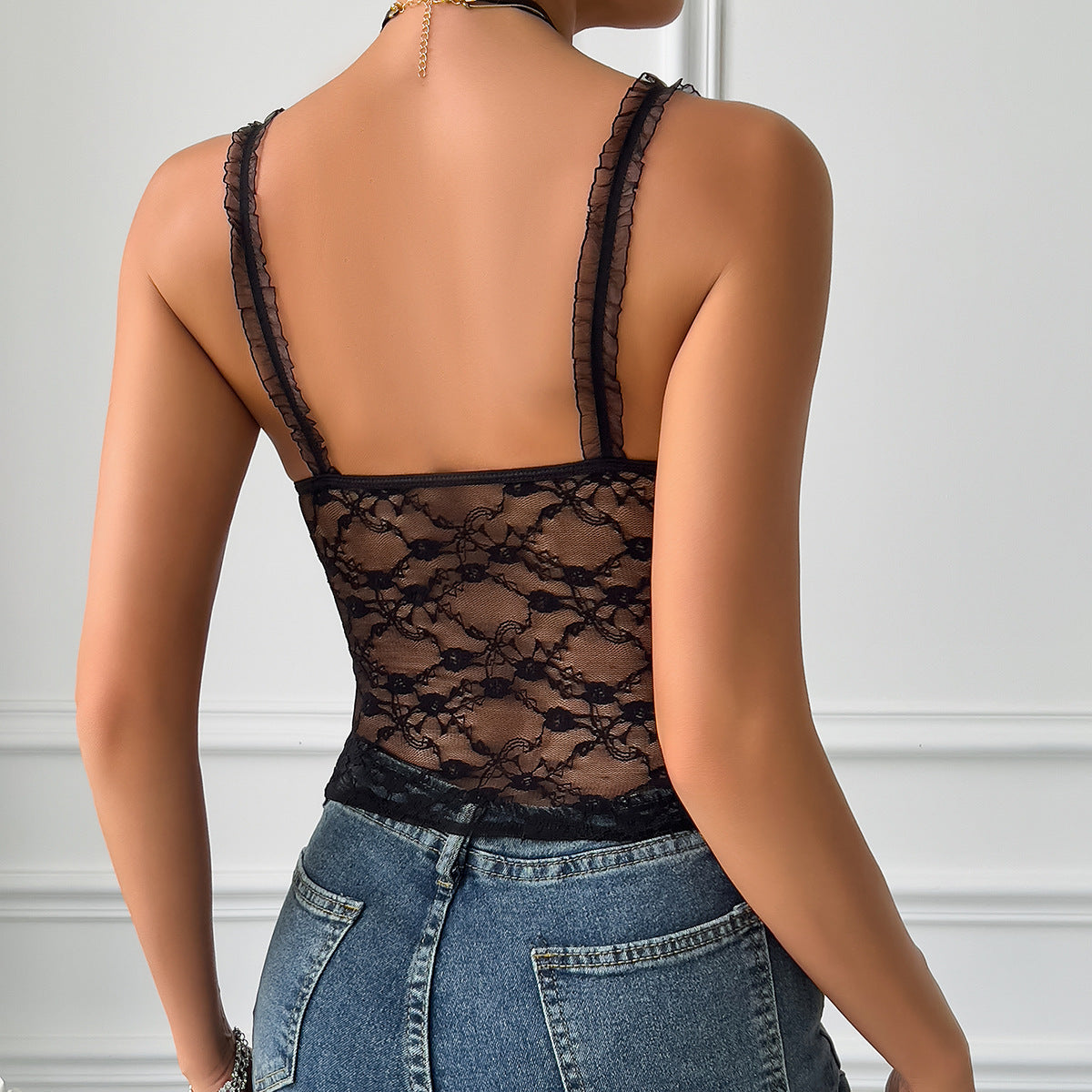 Woman in black lace camisole top and blue jeans, showcasing sling retro corset vest