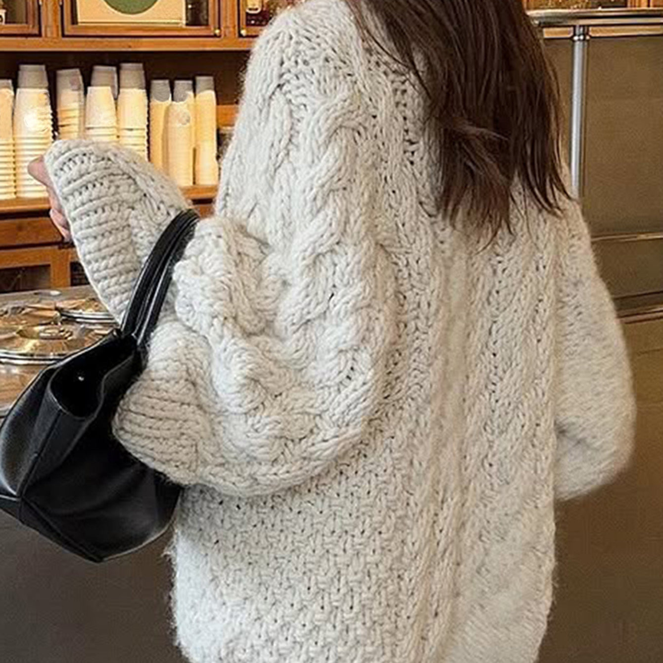 Cream cable knit oversized long sleeve sweater with black leather bag