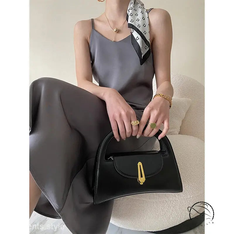 Obsidian black leather handbag with gold hardware on olive green acetate satin dress