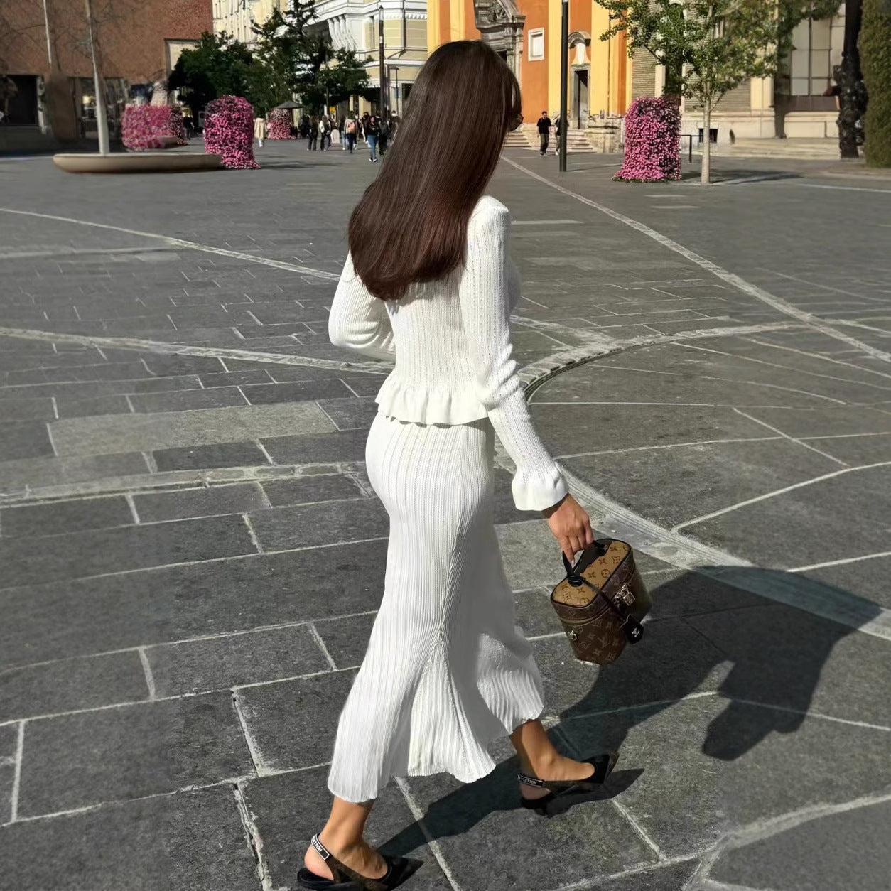 Woman in white knitwear with handbag showcasing elegant fashion dress skirt set