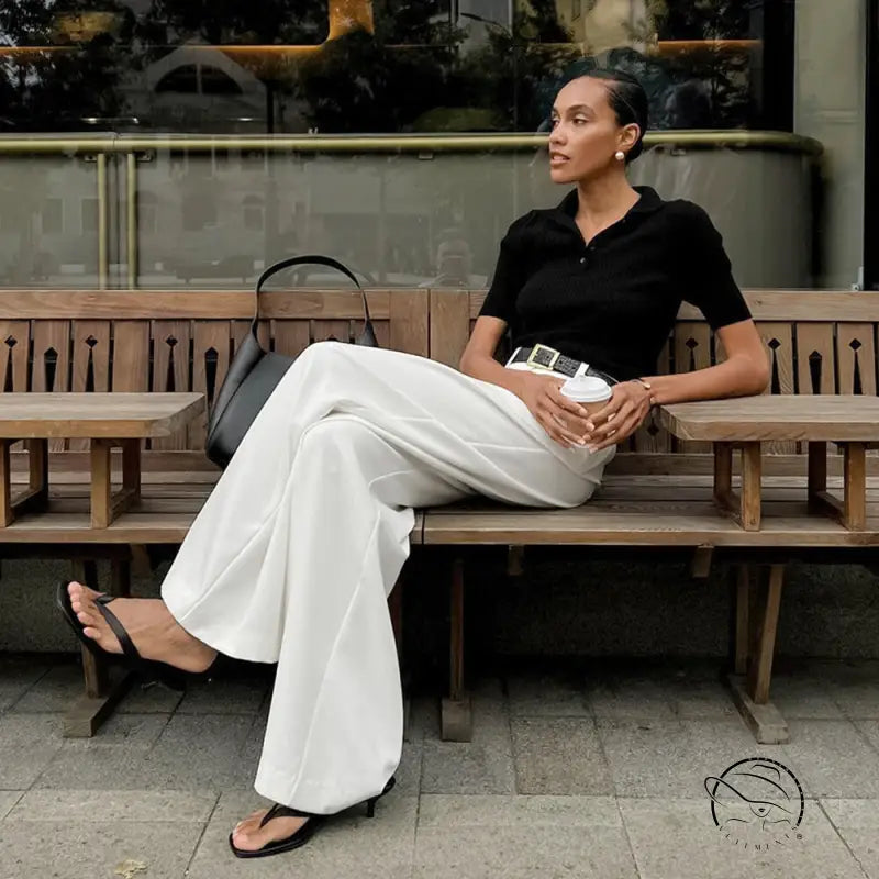 Woman in pure white office trousers on bench with white cup