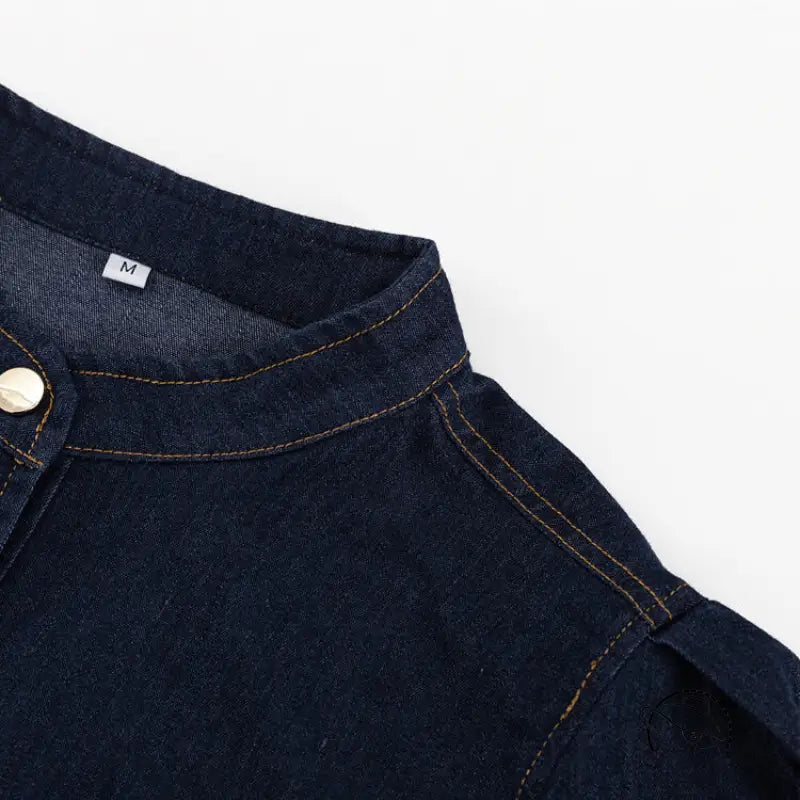 Close-up of dark blue denim shirt fashionable with orange stitching and gold button