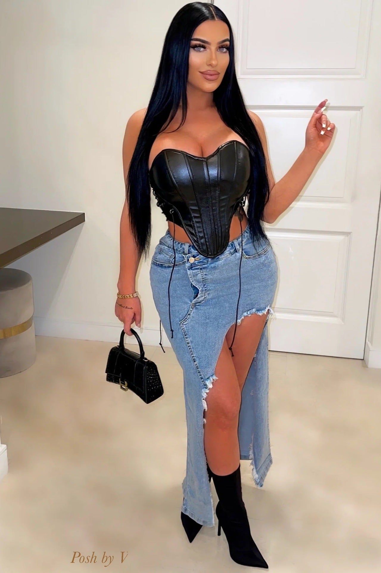 Woman in black corset top, ripped jeans, and knee-high boots showcasing langry fashion ملابس