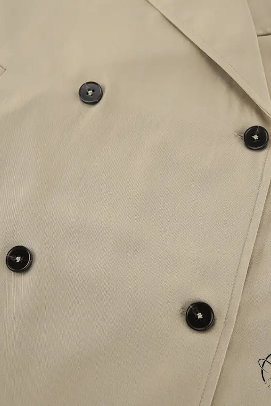 Beige double-breasted trench coat with black buttons and pockets