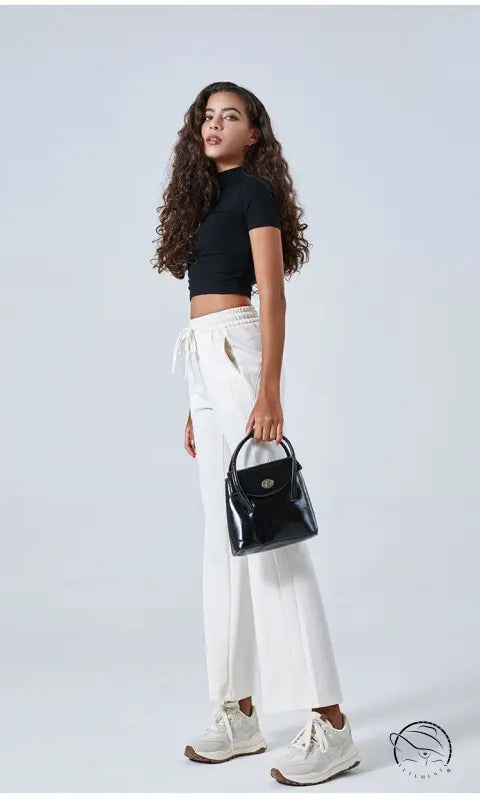 Woman in black crop top, summer air layer drawstring pants, sneakers, handbag
