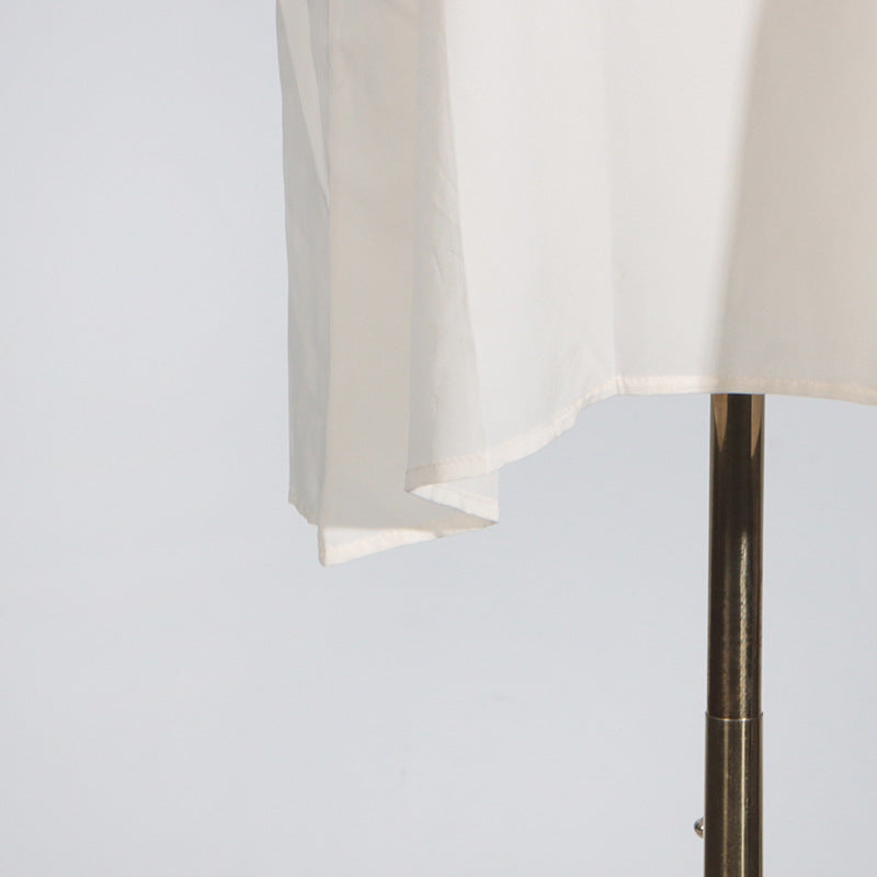 White fabric on a metal stand showcasing elegant fashion clothing with ملابس style