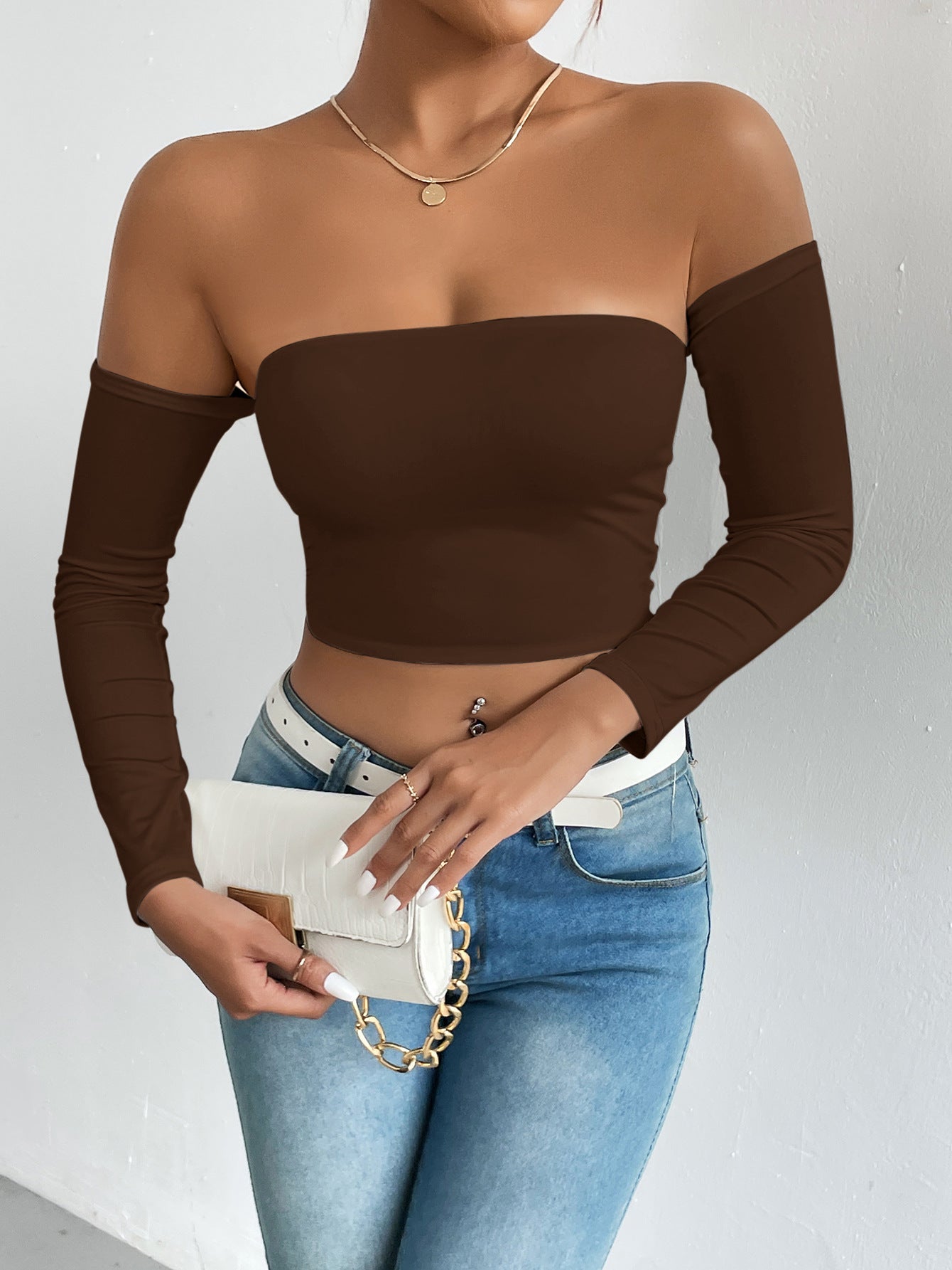 Fashionable brown off-the-shoulder crop top with blue jeans and white accessories