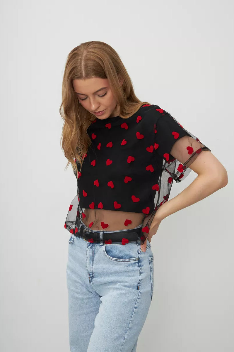 Black mesh crop top with red heart pattern paired with light wash jeans for stylish fashion