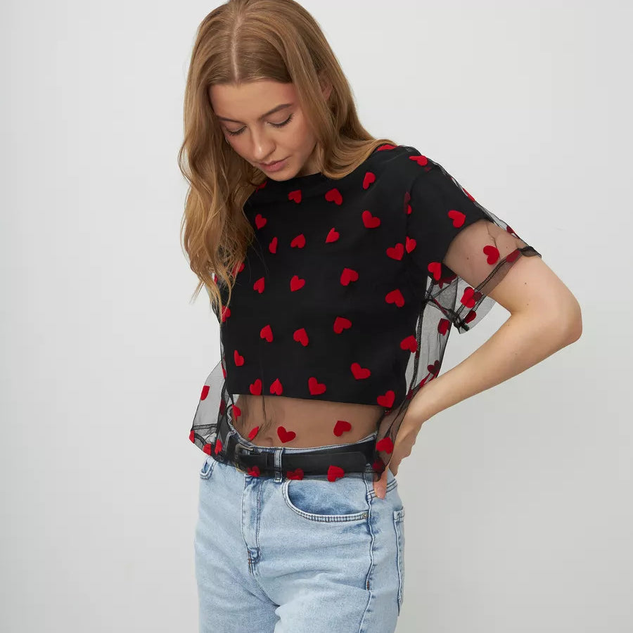 Black mesh crop top with red heart pattern paired with light wash jeans for stylish fashion