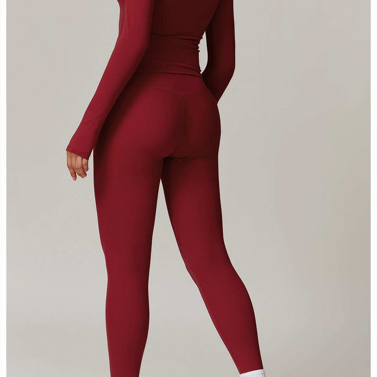 Deep red long-sleeved langry athletic jumpsuit with white socks and chunky sneakers