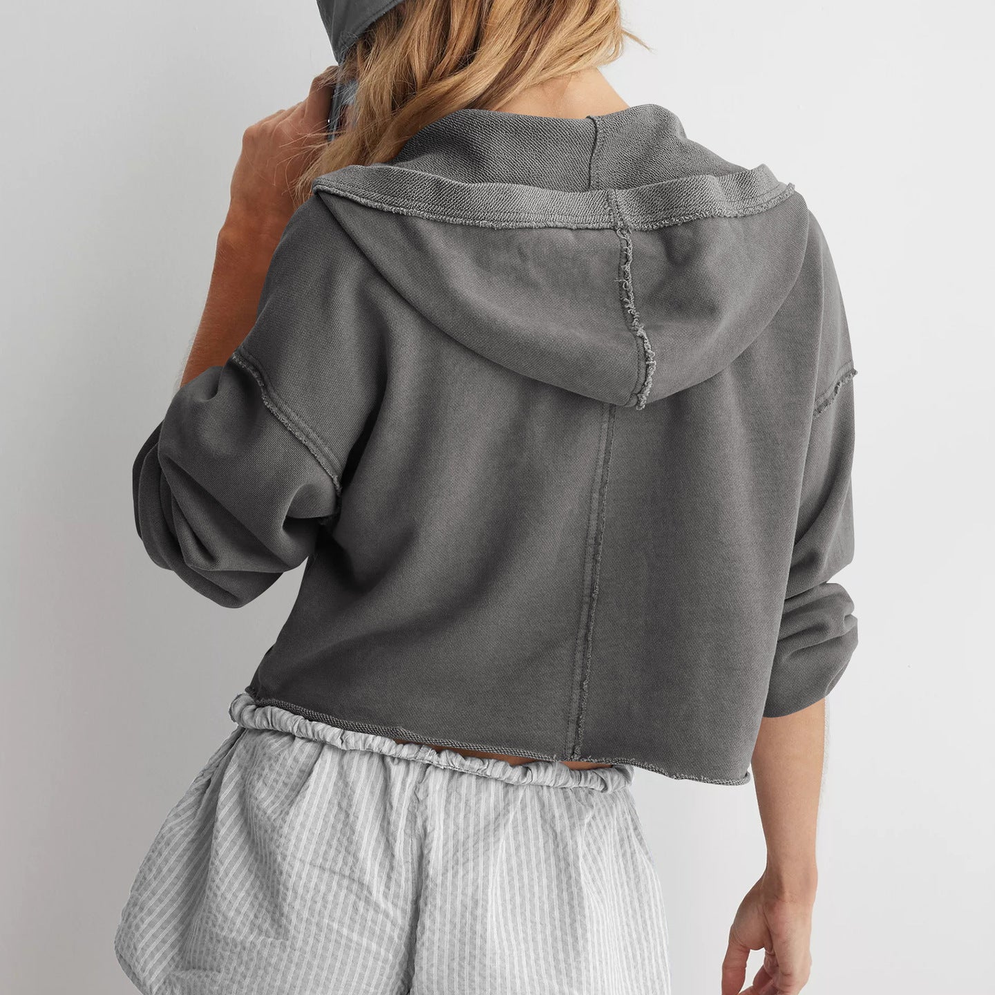 Cropped gray hoodie sweatshirt styled with striped shorts for trendy summer fashion