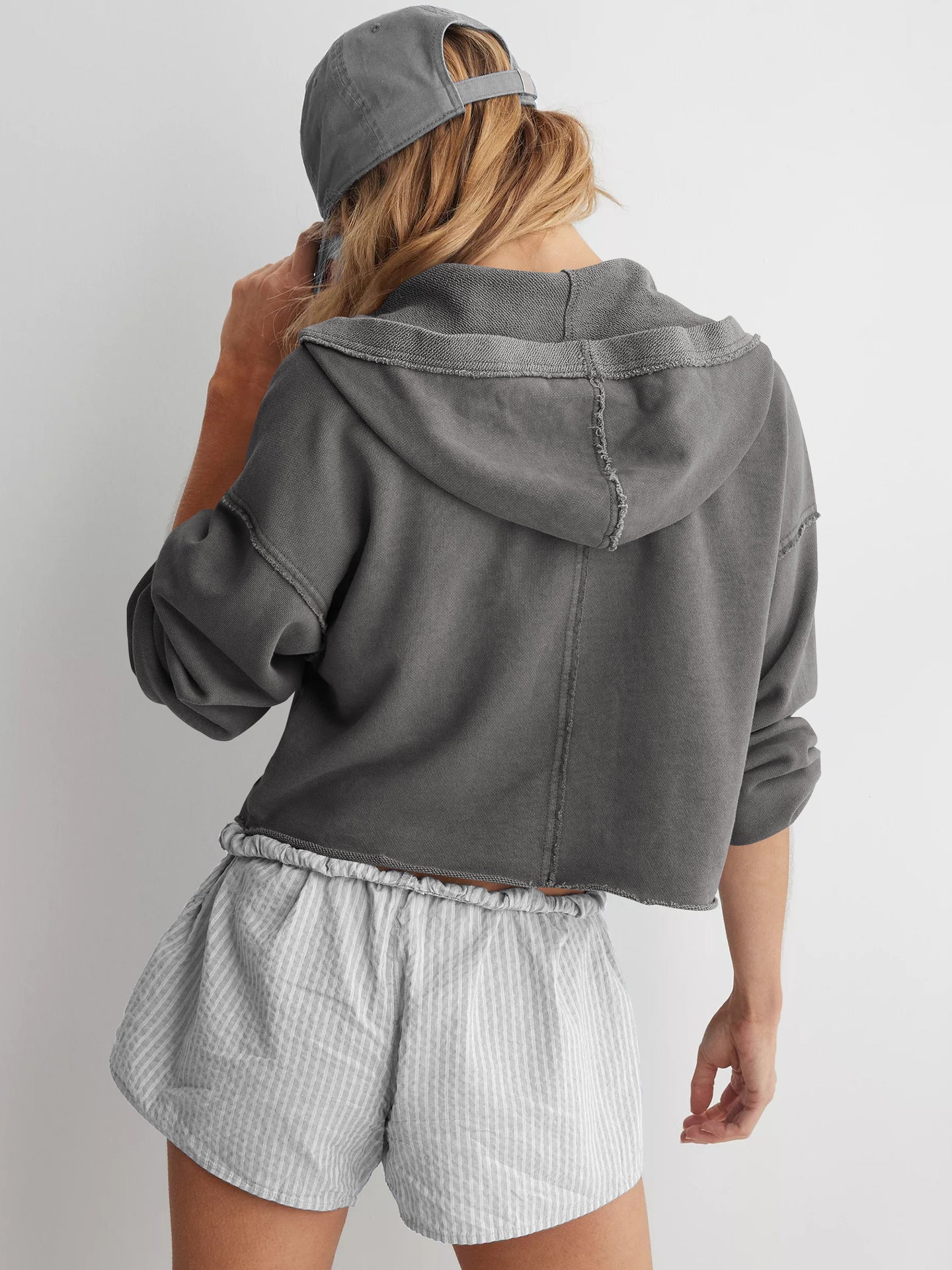 Cropped gray hoodie sweatshirt styled with striped shorts for trendy summer fashion