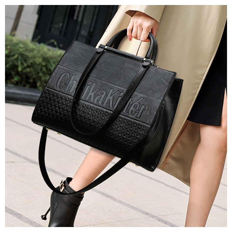 Black leather handbag with textured panels and dual handles for elegant fashion use