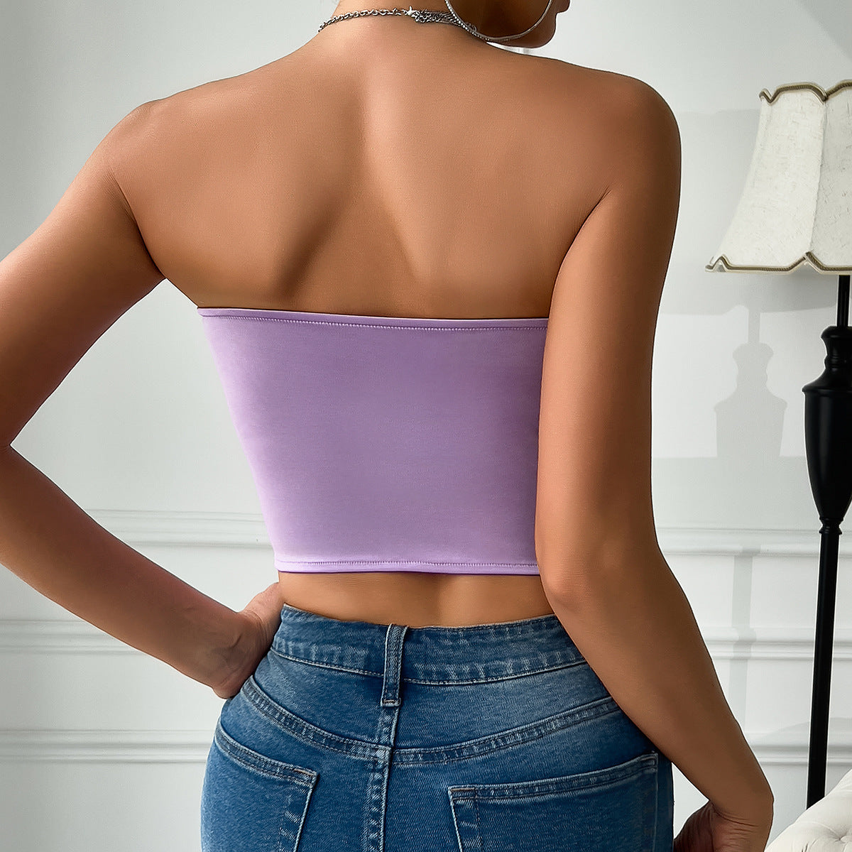 Woman wearing purple low cut satin butterfly tube top with blue jeans