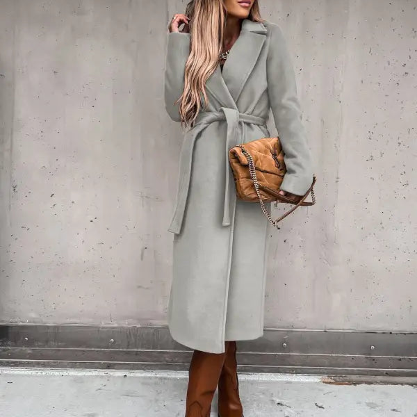 Woman in long gray belted wool coat and brown boots over army green polo collar long sleeved top