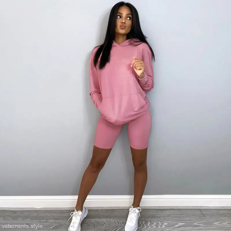 Woman in pink hoodie and bike shorts showcasing the Comfy Sports Sweater Suit with Hooded Long Sleeves