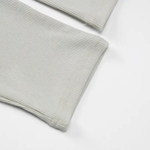 Folded white fabric with ribbed texture, likely a sleeve or cuff of a garment.