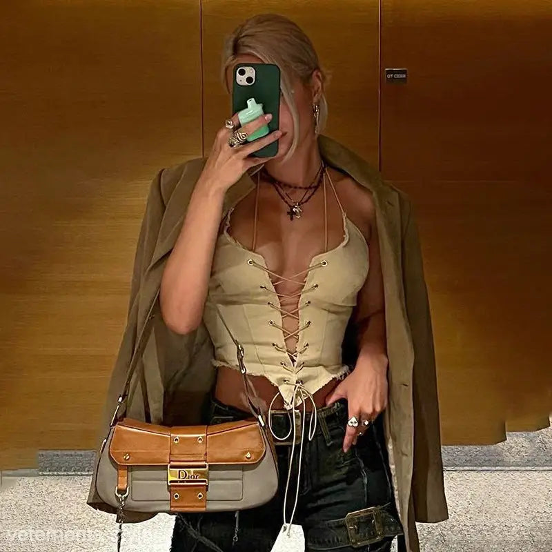 Woman taking mirror selfie wearing a backless bandage corset top with jacket and designer handbag