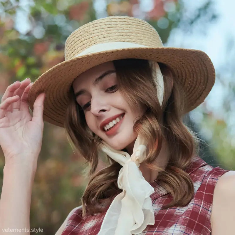 Beige wide-brim sun hat featuring straw boater design with ribbon tie for sun protection