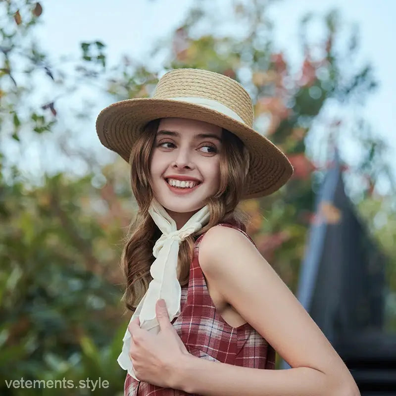 Smiling woman wearing a beige wide-brim sun hat with ribbon band for sun protection